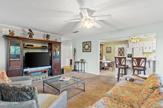 living room featuring visible vents, carpet floors, ceiling fan, a textured ceiling, and crown molding