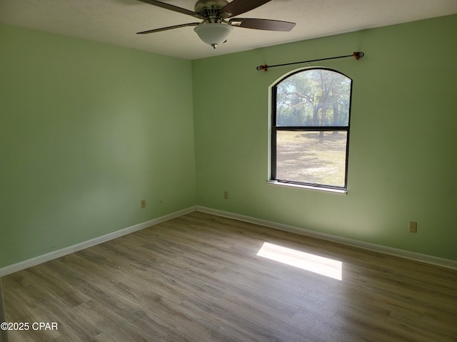 unfurnished room featuring wood finished floors, a ceiling fan, and baseboards