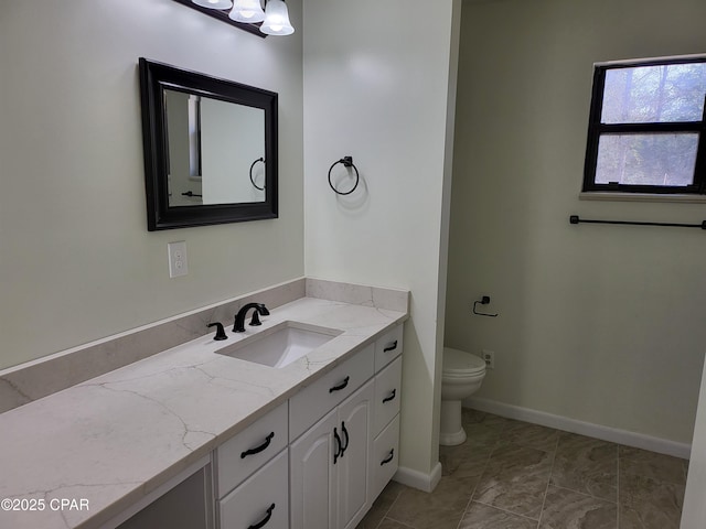 bathroom featuring vanity, toilet, and baseboards