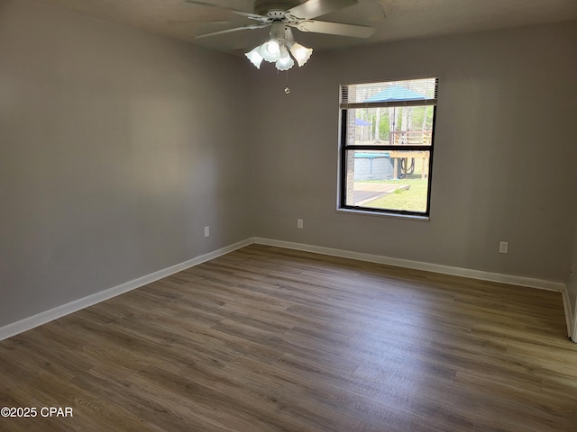 empty room with dark wood-style floors, baseboards, and a ceiling fan