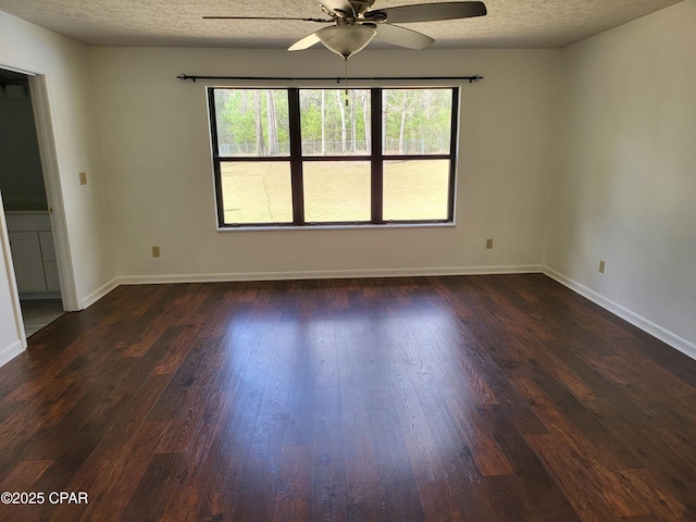 unfurnished room featuring dark wood-style floors, ceiling fan, a textured ceiling, and baseboards