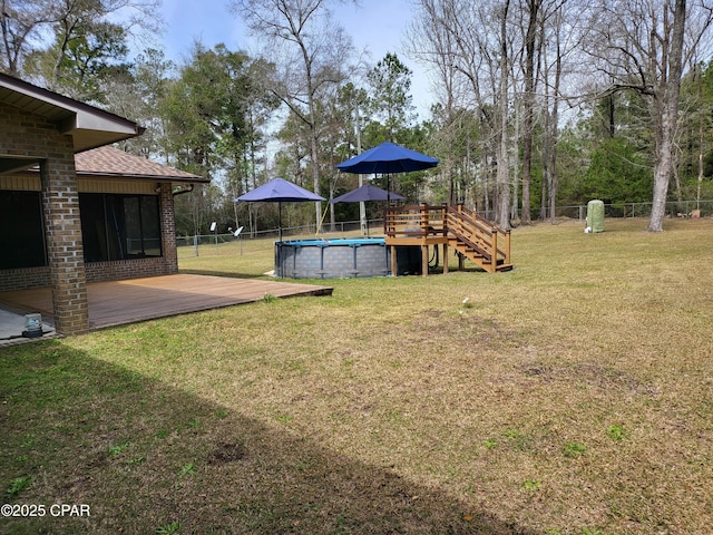 view of yard with fence, an outdoor pool, and a wooden deck