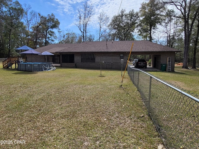 back of property featuring an attached carport, brick siding, and a yard