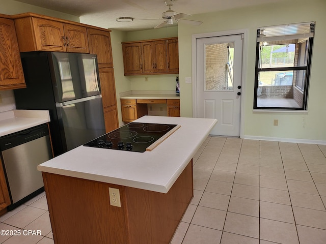 kitchen with light tile patterned floors, light countertops, appliances with stainless steel finishes, brown cabinetry, and built in study area