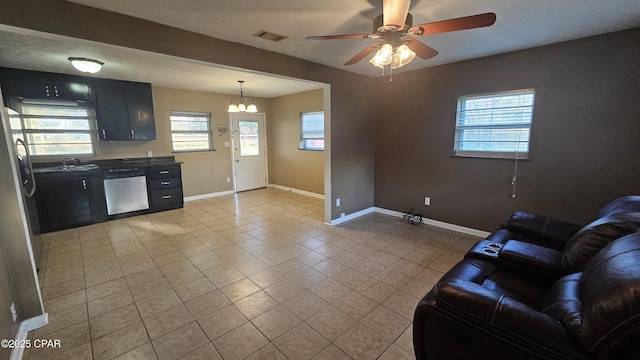 unfurnished living room with light tile patterned floors, baseboards, visible vents, a sink, and ceiling fan with notable chandelier