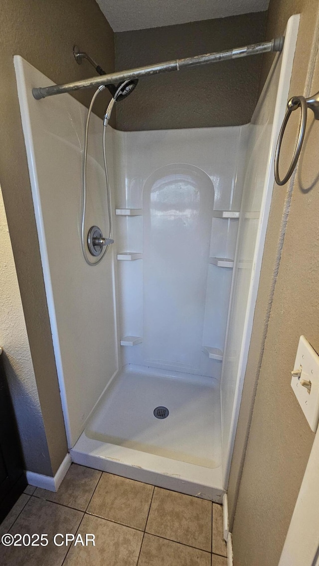 full bathroom featuring a stall shower, tile patterned flooring, and baseboards