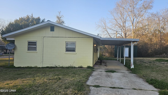 view of side of property with an attached carport, a lawn, and driveway