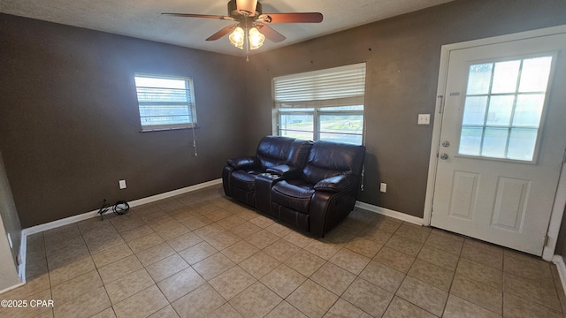 living area with a healthy amount of sunlight, baseboards, a ceiling fan, and light tile patterned flooring