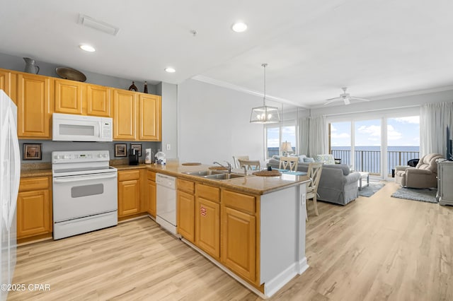 kitchen with crown molding, light wood finished floors, a sink, white appliances, and a peninsula