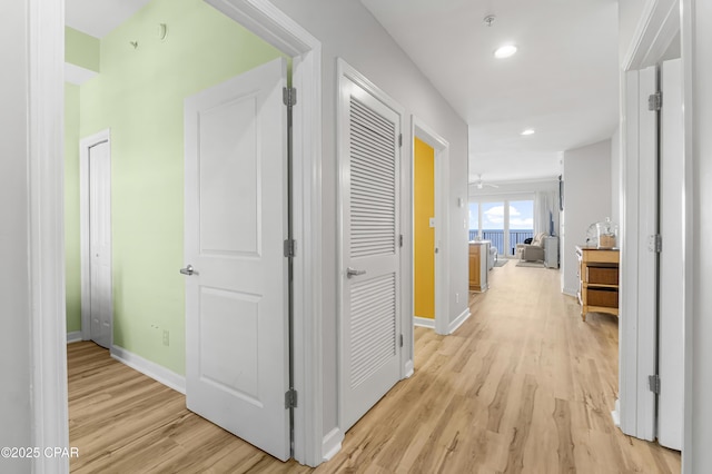 hallway featuring light wood-type flooring, baseboards, and recessed lighting