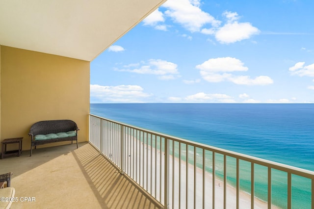 balcony with a water view and a view of the beach