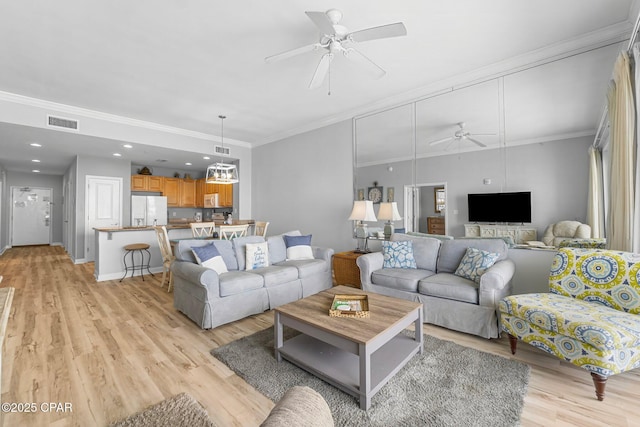 living area featuring light wood-style floors, visible vents, and ornamental molding