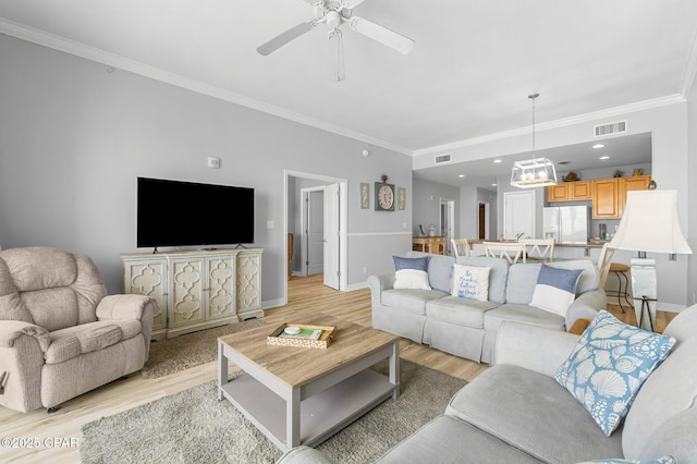 living area featuring ornamental molding, light wood-type flooring, visible vents, and baseboards