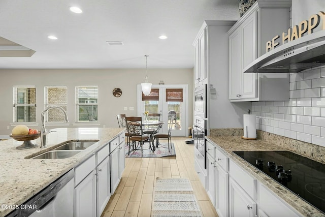 kitchen featuring tasteful backsplash, wall chimney exhaust hood, appliances with stainless steel finishes, wood tiled floor, and a sink