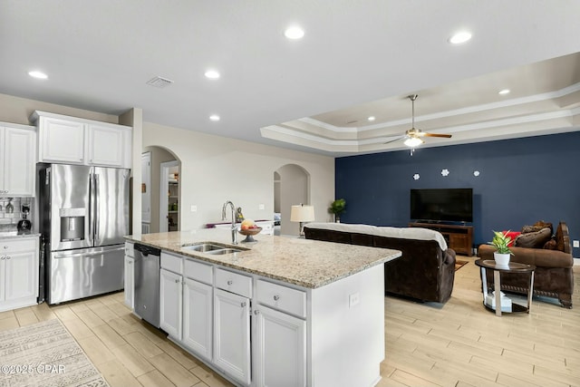 kitchen with white cabinets, appliances with stainless steel finishes, wood tiled floor, a tray ceiling, and a sink