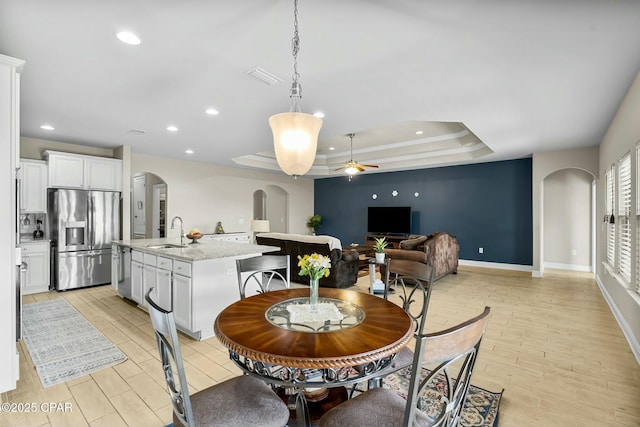 dining area featuring arched walkways, recessed lighting, visible vents, light wood finished floors, and a tray ceiling