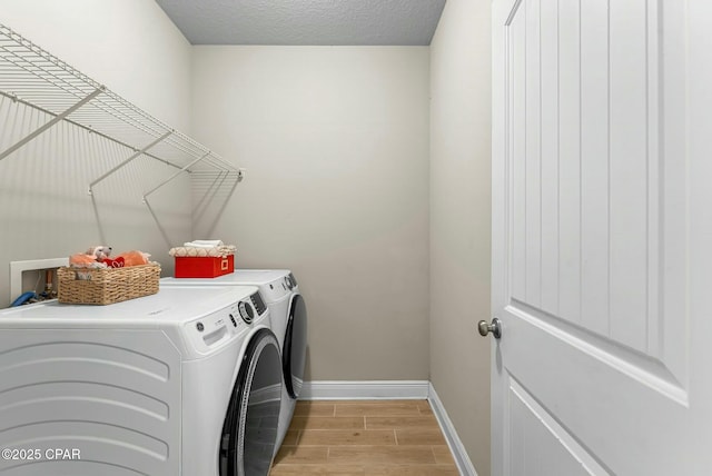 laundry room with laundry area, baseboards, a textured ceiling, wood finish floors, and separate washer and dryer