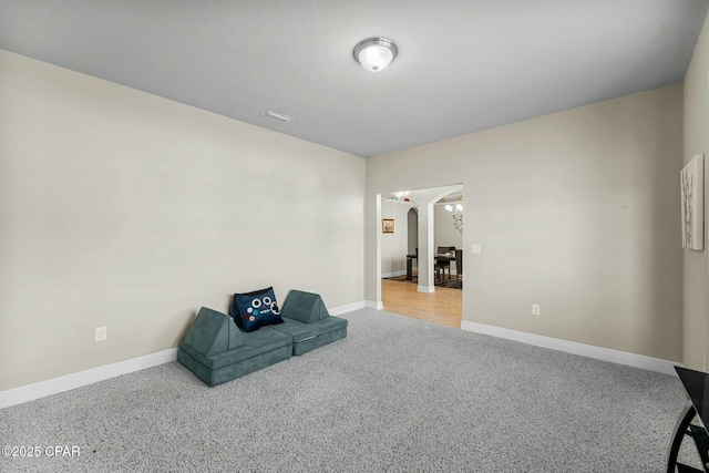 living area with arched walkways, carpet, visible vents, and baseboards