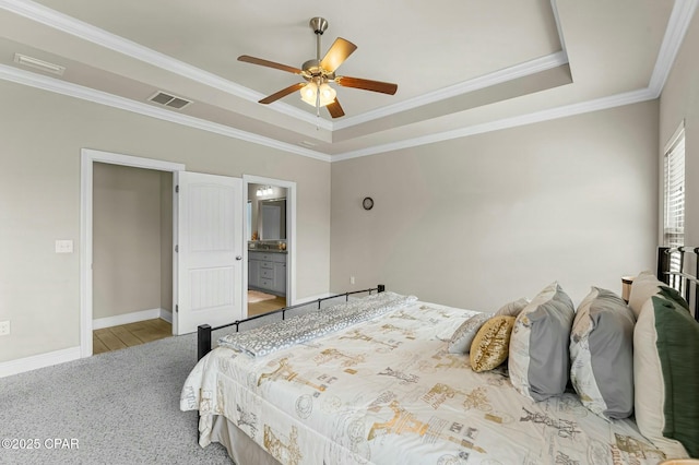 bedroom with baseboards, visible vents, a tray ceiling, and crown molding