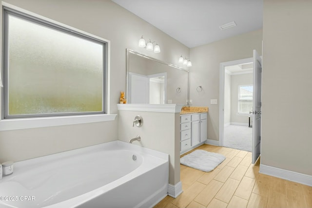 bathroom featuring a garden tub, visible vents, wood tiled floor, vanity, and baseboards