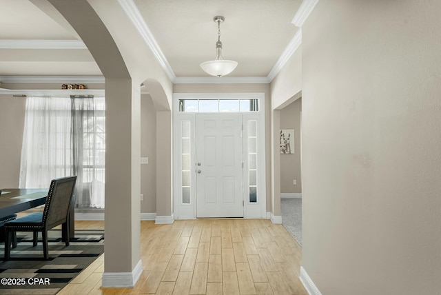 entryway with arched walkways, ornamental molding, light wood-style flooring, and baseboards