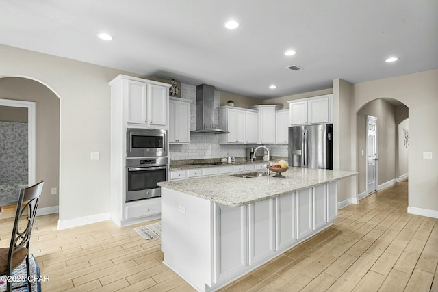 kitchen featuring visible vents, decorative backsplash, stainless steel appliances, wood finish floors, and wall chimney range hood