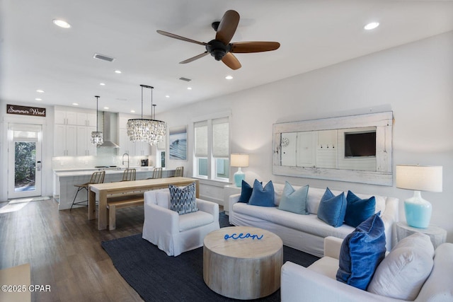 living area with recessed lighting, visible vents, dark wood-type flooring, and ceiling fan with notable chandelier