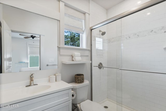 full bathroom featuring vanity, a shower stall, toilet, and a ceiling fan