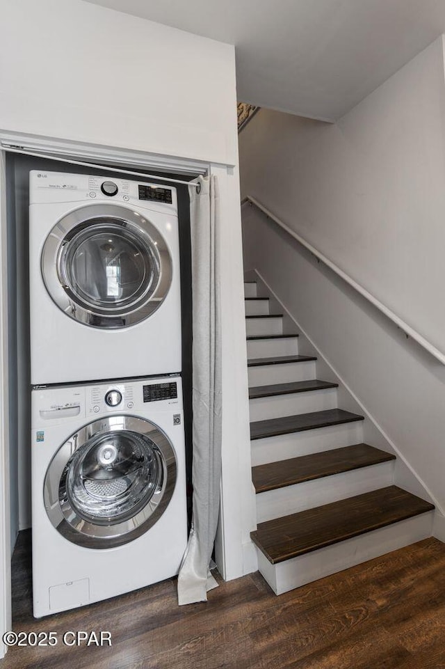 laundry area with laundry area, wood finished floors, and stacked washer and dryer