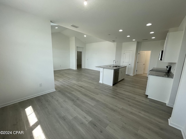 kitchen featuring a center island with sink, visible vents, open floor plan, white cabinetry, and a sink