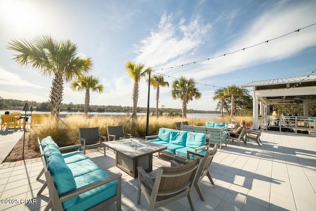 view of patio with a water view and an outdoor living space with a fire pit