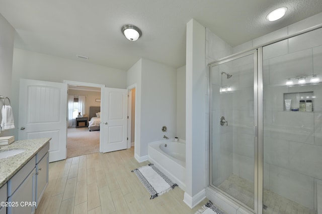 146 Bayou Manor Rd, Santa Rosa Beach, FL 32459 - ensuite bathroom with a textured ceiling, a shower stall, wood finished floors, vanity, and a garden tub