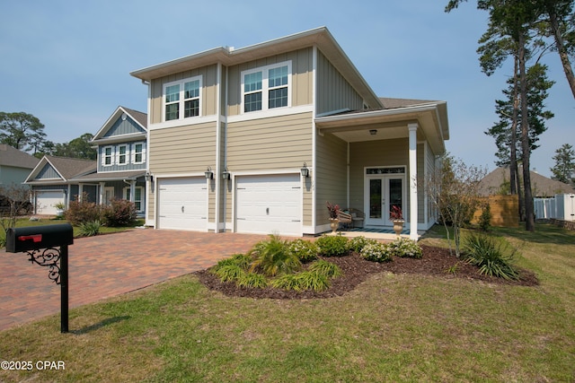146 Bayou Manor Rd, Santa Rosa Beach, FL 32459 - view of front of house with an attached garage, french doors, board and batten siding, decorative driveway, and a front yard