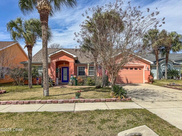 view of front facade featuring an attached garage, driveway, a front lawn, and stucco siding