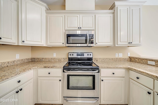 kitchen featuring appliances with stainless steel finishes, light stone countertops, and white cabinets