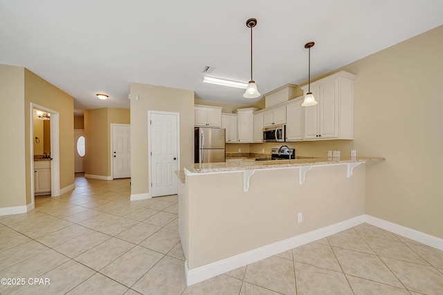 kitchen with a breakfast bar area, light tile patterned flooring, a peninsula, and appliances with stainless steel finishes