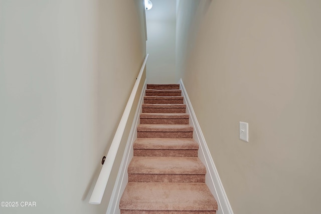 stairway featuring baseboards and carpet floors