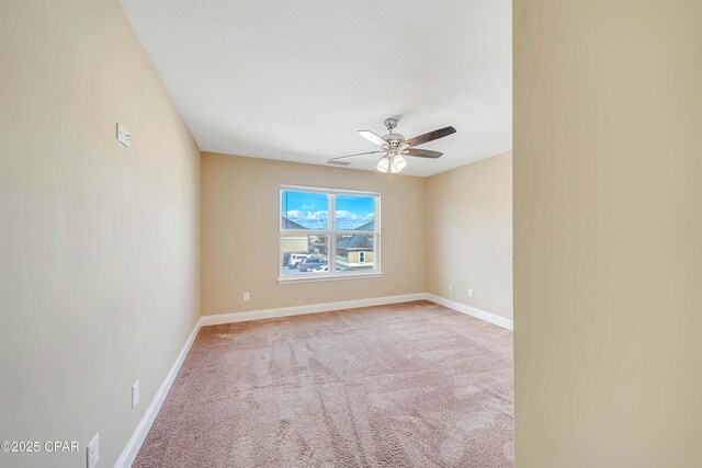 spare room with baseboards, light carpet, and ceiling fan