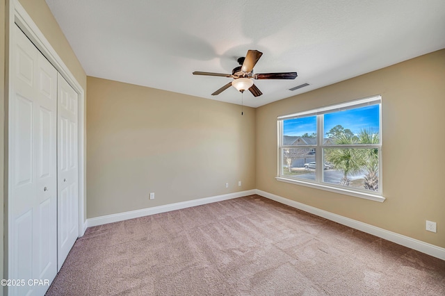 unfurnished bedroom featuring carpet floors, a closet, ceiling fan, baseboards, and visible vents