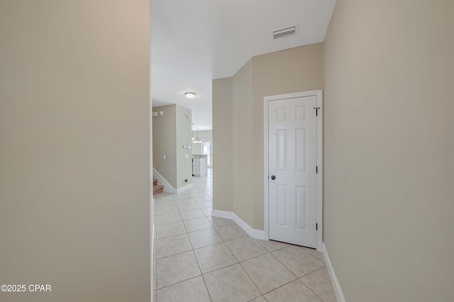 hallway featuring light tile patterned floors, visible vents, stairs, and baseboards