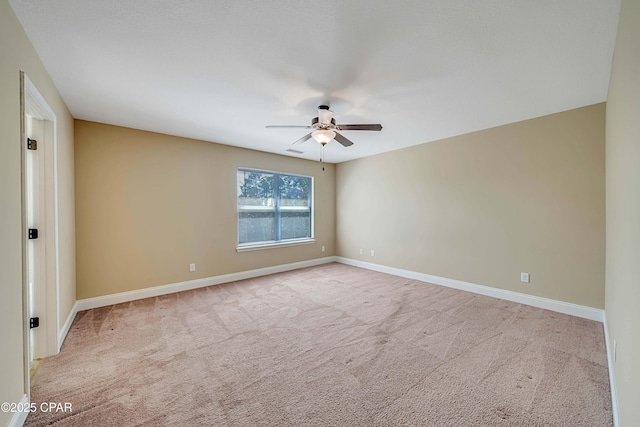 carpeted spare room with a ceiling fan and baseboards
