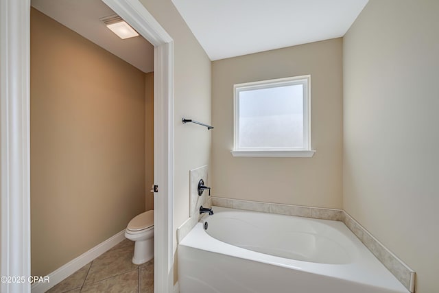 full bath featuring a garden tub, toilet, tile patterned flooring, and baseboards