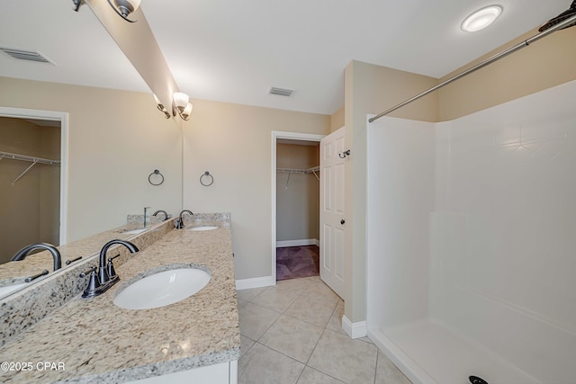bathroom featuring a sink, double vanity, visible vents, a stall shower, and tile patterned floors