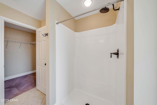 full bath with a spacious closet, a stall shower, and tile patterned flooring