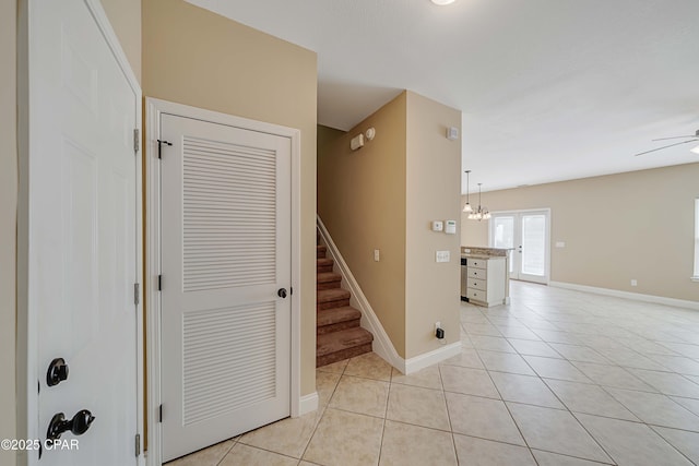 staircase featuring tile patterned flooring, a ceiling fan, and baseboards