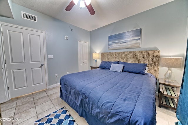 bedroom with light tile patterned floors, a ceiling fan, visible vents, a closet, and a textured ceiling