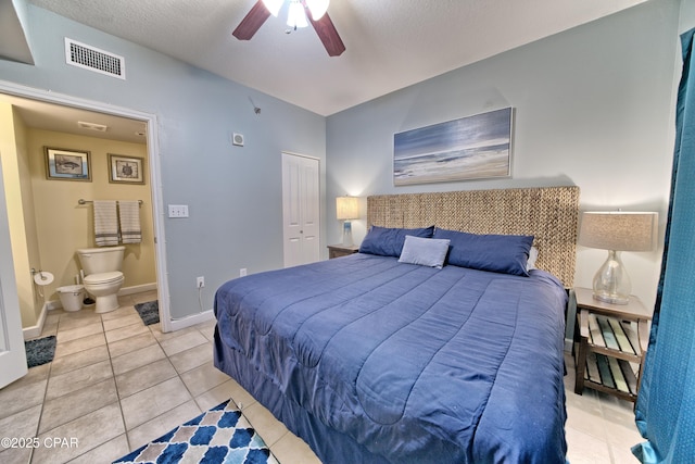 bedroom with light tile patterned floors, a ceiling fan, baseboards, visible vents, and ensuite bath