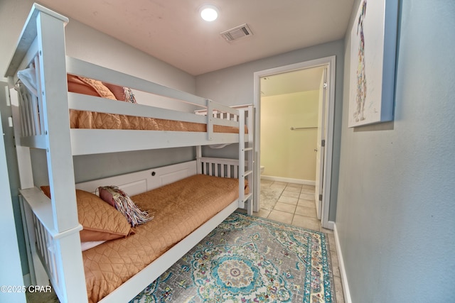 bedroom with tile patterned floors, visible vents, baseboards, and ensuite bathroom