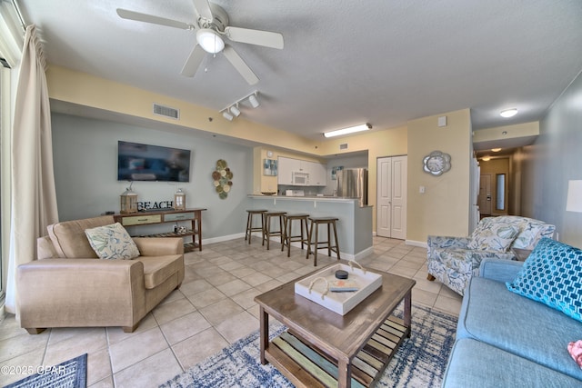 living room featuring visible vents, a ceiling fan, light tile patterned flooring, a textured ceiling, and baseboards