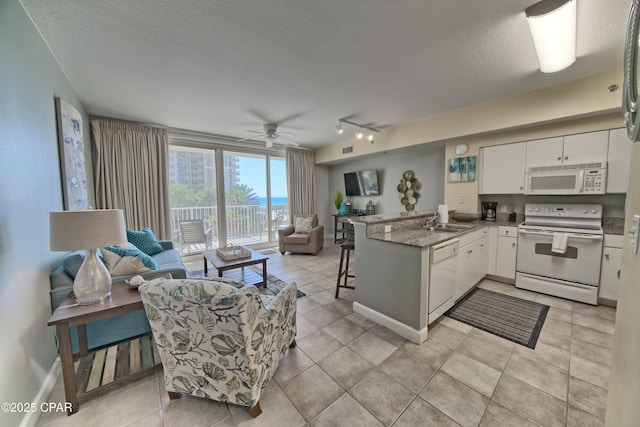 kitchen with a sink, white appliances, a peninsula, and open floor plan